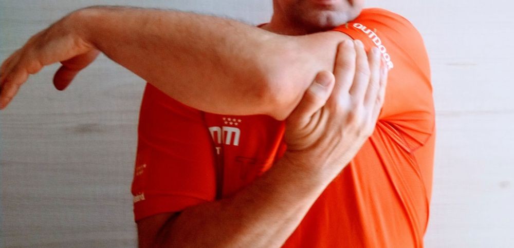 Un deportista realiza ejercicios de estiramiento del hombro