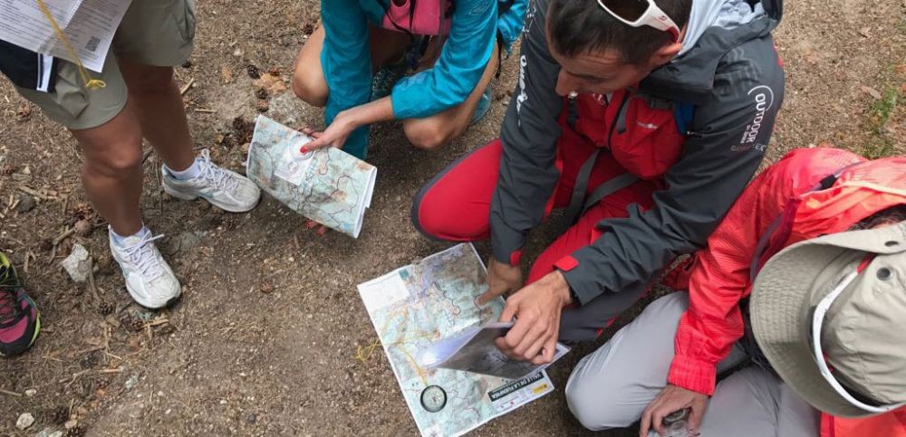 Un profesor de la escuela madrileña de alta montaña muestra a los alumnos un mapa y una brújula sobre el terreno.